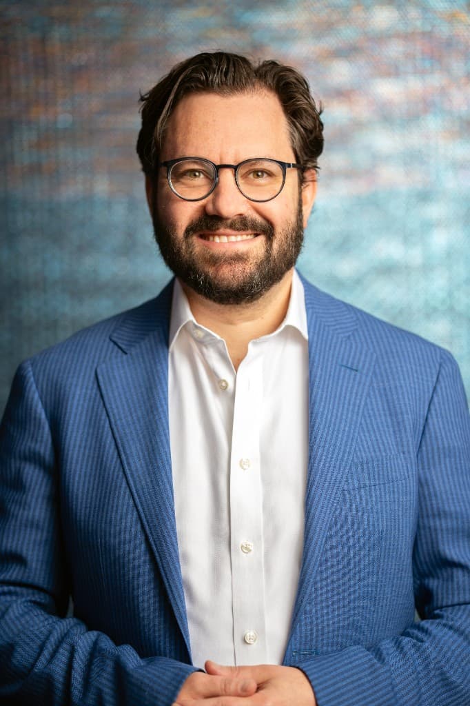 Dr. Jonathan Kirschner, wearing glasses and a blue suit, facing the camera.